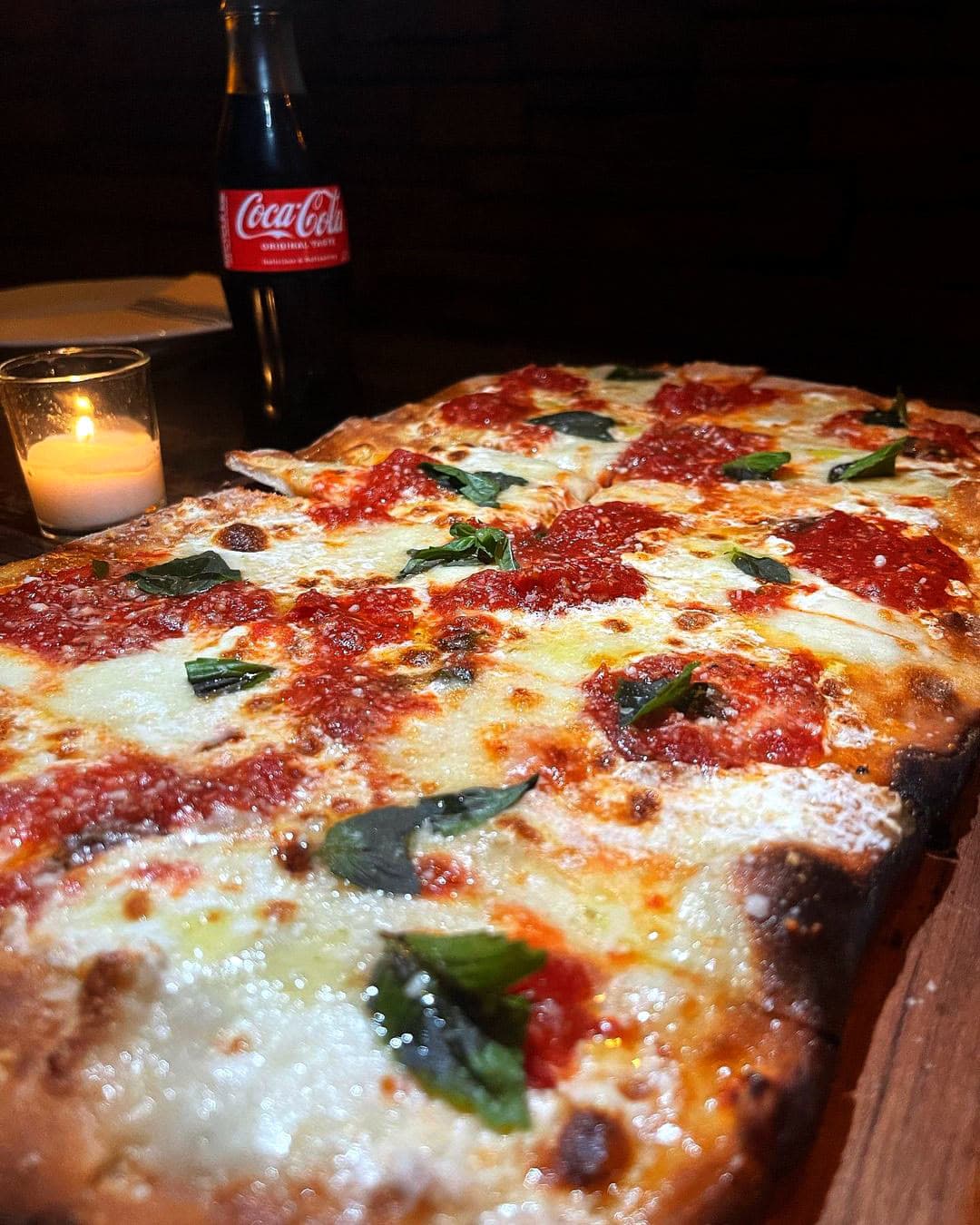 Square slices of Little Charli pizza by candlelight