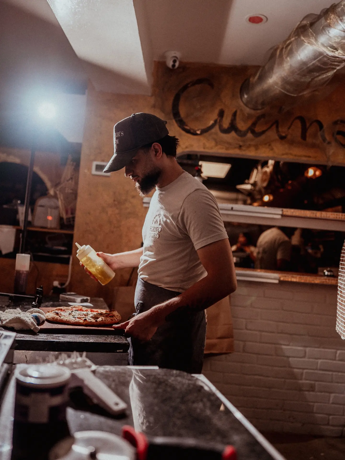 Giovanni Barbato finishing a pizza with olive oil at Forno d'Oro
