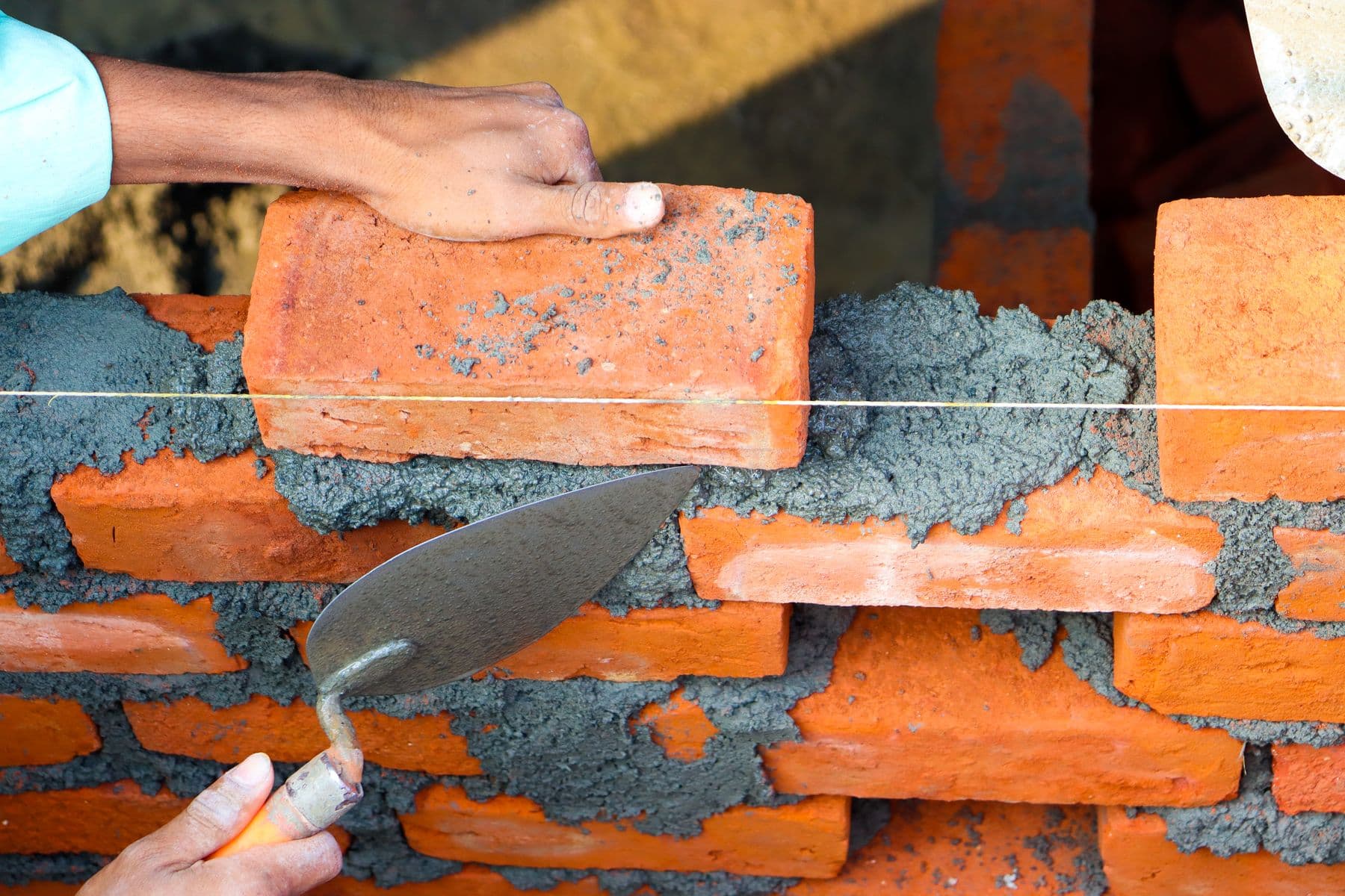 Hands laying bricks with mortar