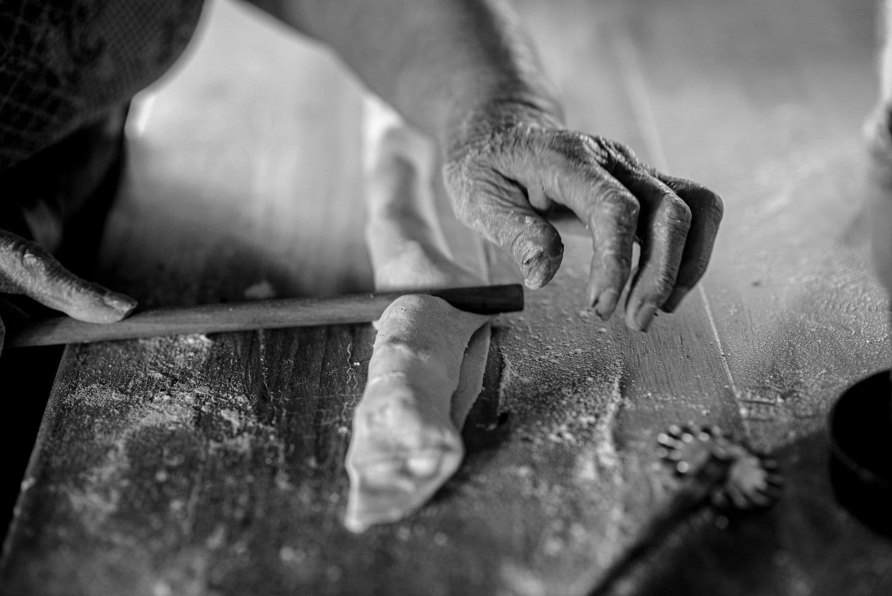 Hands shaping pastry, in black and white