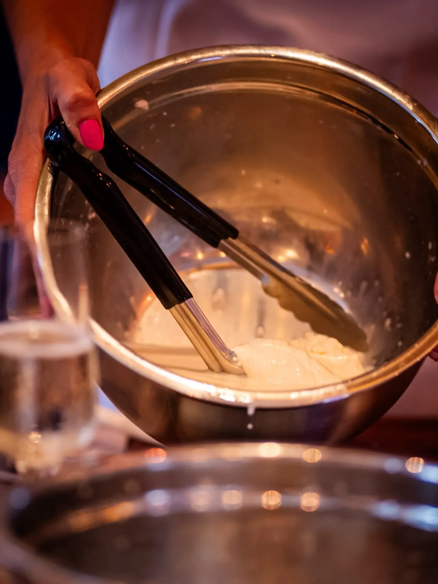 Fresh mozzarella lifted from hot water with tongs